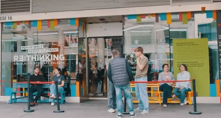 Menschen stehen vor einem bunten Pop-up-Raum in Stuttgart, der für kreative Ideen und Projekte wirbt.