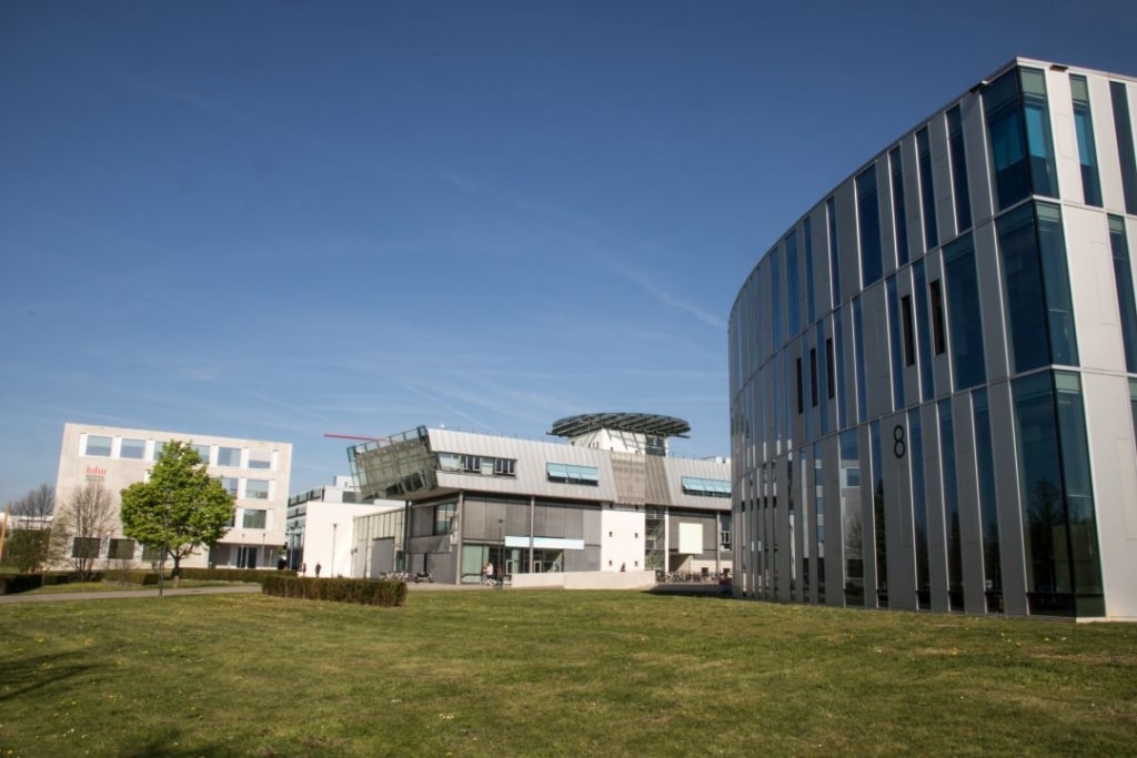 Moderne Architektur von Gebäuden in einer grünen Parklandschaft unter blauem Himmel.